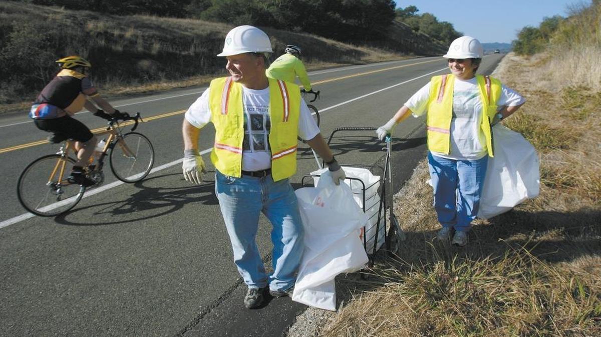 Paul and Mary Speidell pick up trash as traffic speeds by on Highway 46 West.