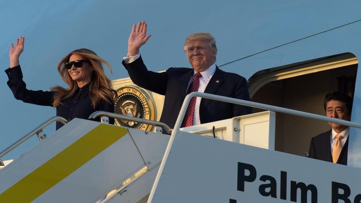 President Donald Trump, center, and first lady Melania Trump, left, wave from the top of the steps of Air Force One at Palm Beach International Airport in West Palm Beach, Fla., Friday, Feb. 10, 2017, as Japanese Prime Minister Shinzo Abe, right, waits to exit the plane.