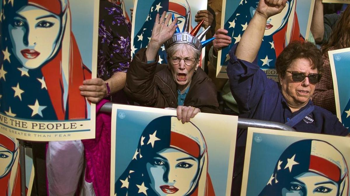In this Feb. 19, 2017 file photo, people carry posters during a rally against President Donald Trump’s executive order banning travel from seven Muslim-majority nations, in New York's Times Square.