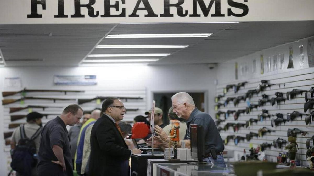 In this Dec. 9, 2015, photo, sales associate Mike Conway, right, shows Paul Angulo a firearm at Bullseye Sport gun shop in Riverside.