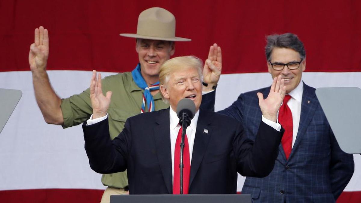 In this July 24, 2017 file photo, President Donald Trump, front left, gestures as former boys scouts, Interior Secretary Ryan Zinke, left, and Energy Secretary Rick Perry, watch at the 2017 National Boy Scout Jamboree at the Summit in Glen Jean, W.Va. As former U.S. Interior Secretary Zinke exits Washington amid a cloud of unresolved ethics investigations, he says he has lived up to the conservation ideals of Teddy Roosevelt and insists the myriad allegations against him will be proven untrue.