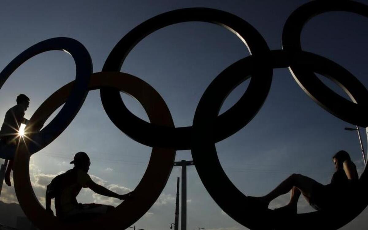 In this Aug. 1, 2016, photo, people pose for a photo with the Olympic Rings at the Olympic Park in Rio de Janeiro, Brazil.