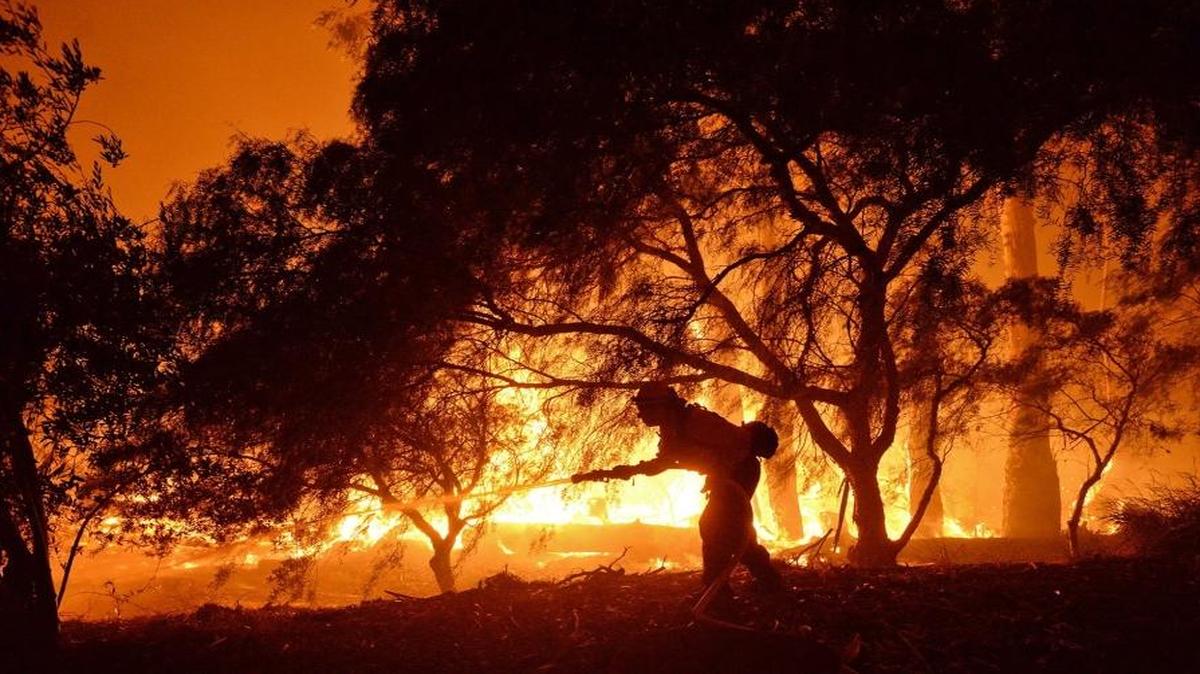 In this photo provided by the Santa Barbara County Fire Department, a firefighter knocks down flames as they approach a ranch near the Las Flores Canyon area west of Goleta, Calif., in the early morning hours of Thursday, June 16, 2016.