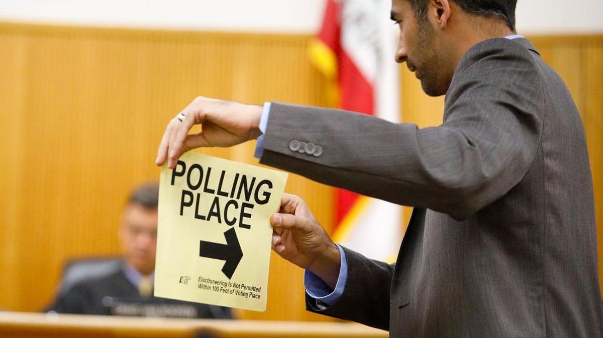 Deputy Attorney General Abtin Amir holds a polling place sign, with small writing that says "electioneering is not permitted within 100 feet of voting place" and asks witness Alvah Hicks if these were posted at the Elks Lodge in Atascadero, during the Edith Meta Knight trial for misdemeanor electioneering at a polling place. Hicks said they were.