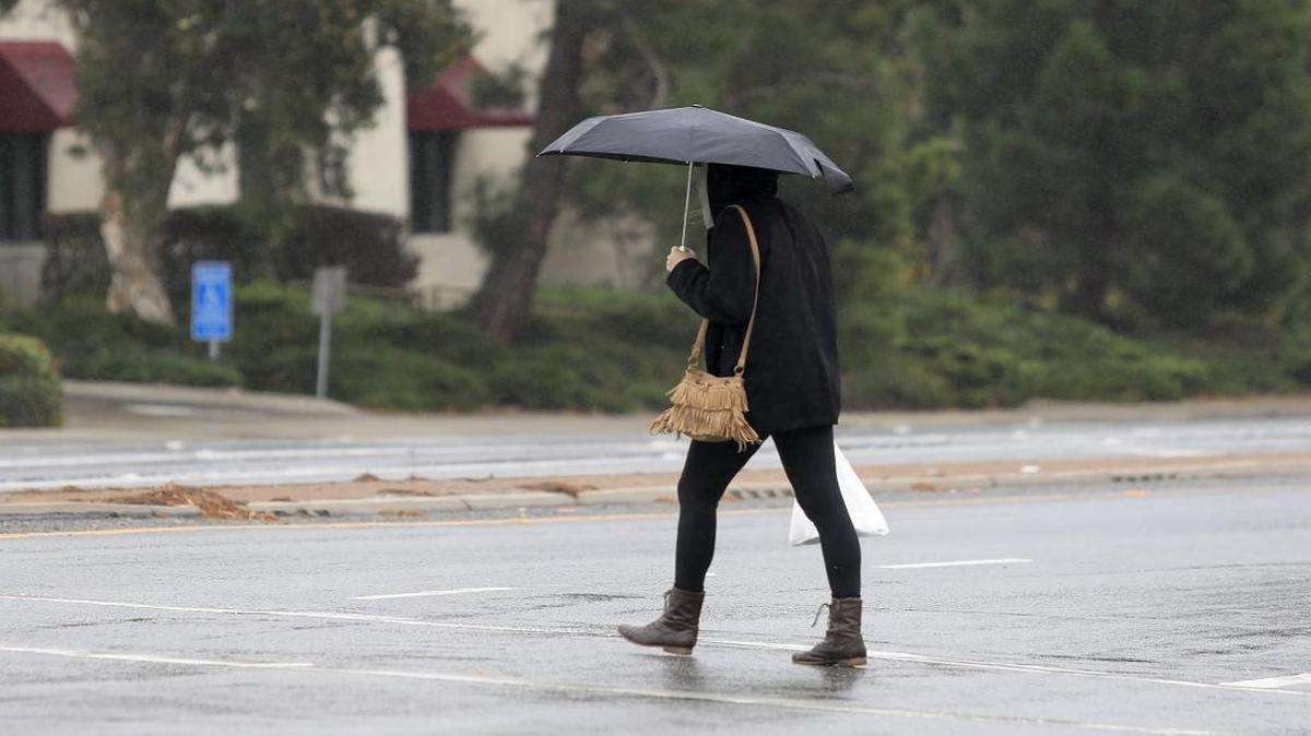 A woman crosses the intersection of Foothill Road and Santa Rosa in the rain in San Luis Obispo.