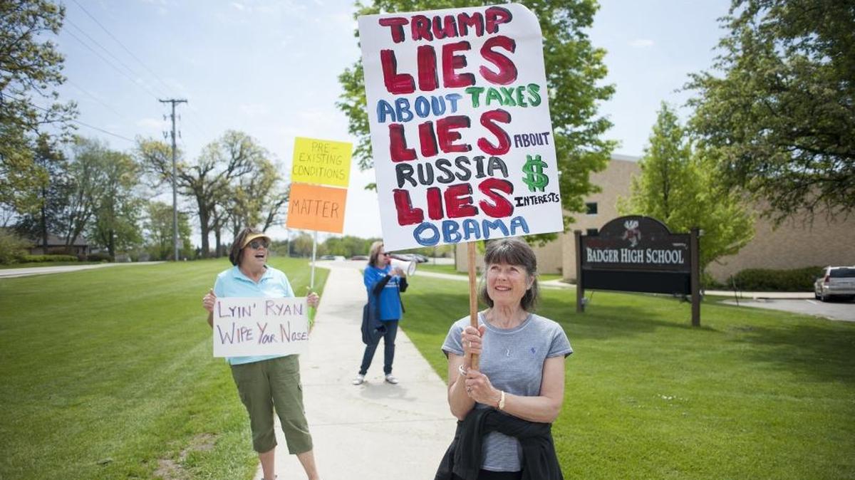 Sonette Tippens from the Town of Linn holds a sign in protest of House Speaker Paul Ryan's visit to address high school students Friday, May 12, 2017, at Badger High School in Lake Geneva, Wis.