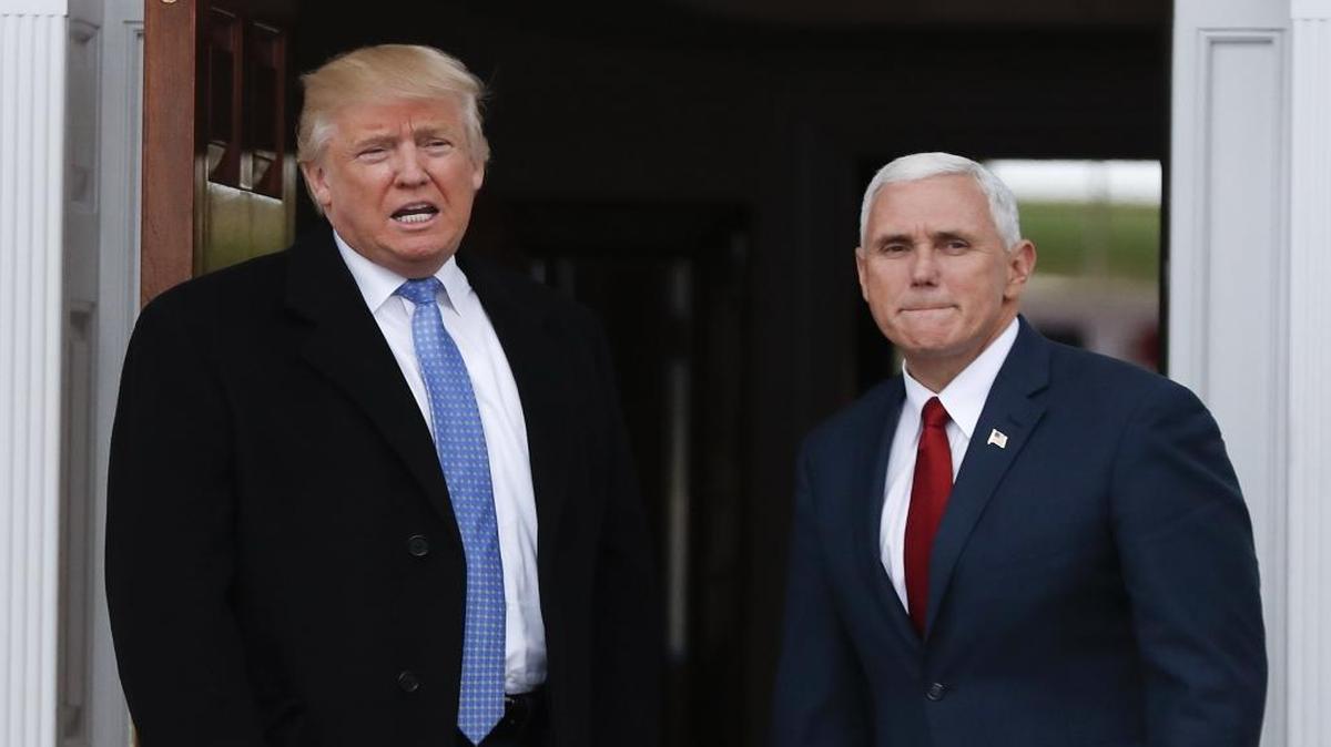 President-elect Donald Trump, left, talks to media as he and Vice President-elect Mike Pence arrive at the Trump National Golf Club Bedminster clubhouse.