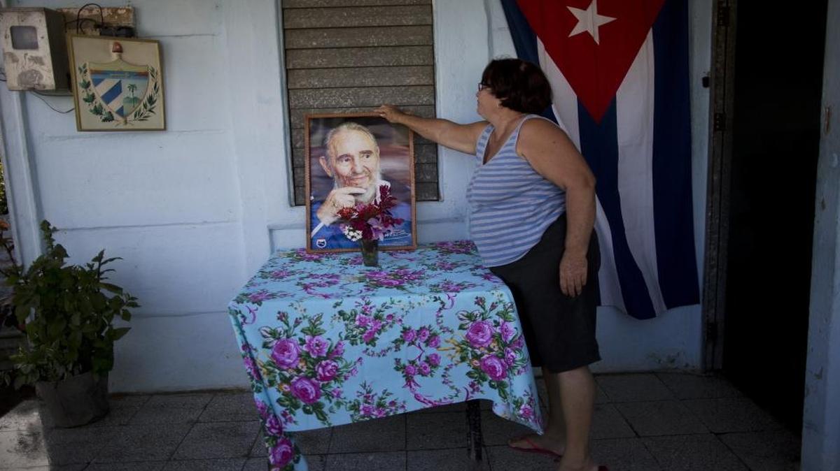 Veronica Santo accommodates a photograph of Fidel Castro on her porch in Camaguey, Cuba, Wednesday, Nov. 30, 2016.