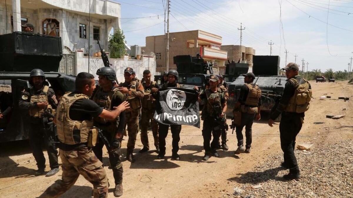 Iraq’s elite counterterrorism forces celebrate Wednesday, April 13, as they hold a flag of the Islamic State group that they captured during a military operation to regain control of Hit, a town 85 miles west of Baghdad.