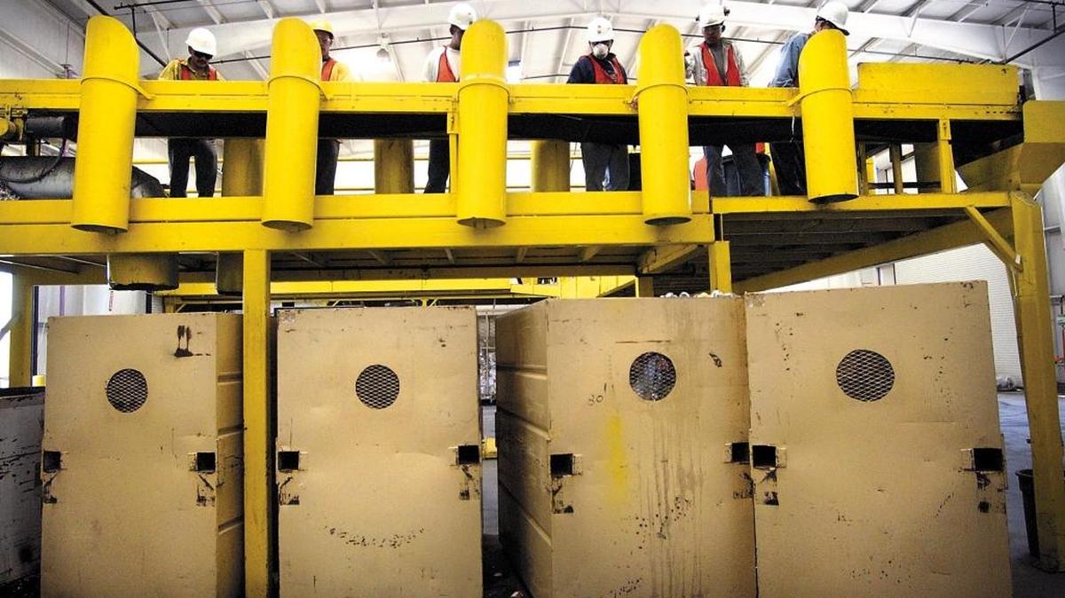 Workers sort through the various recyclables on a conveyer belt and drop them down shoots into the large item-specific bins below them at the North County recycling facility in Templeton.