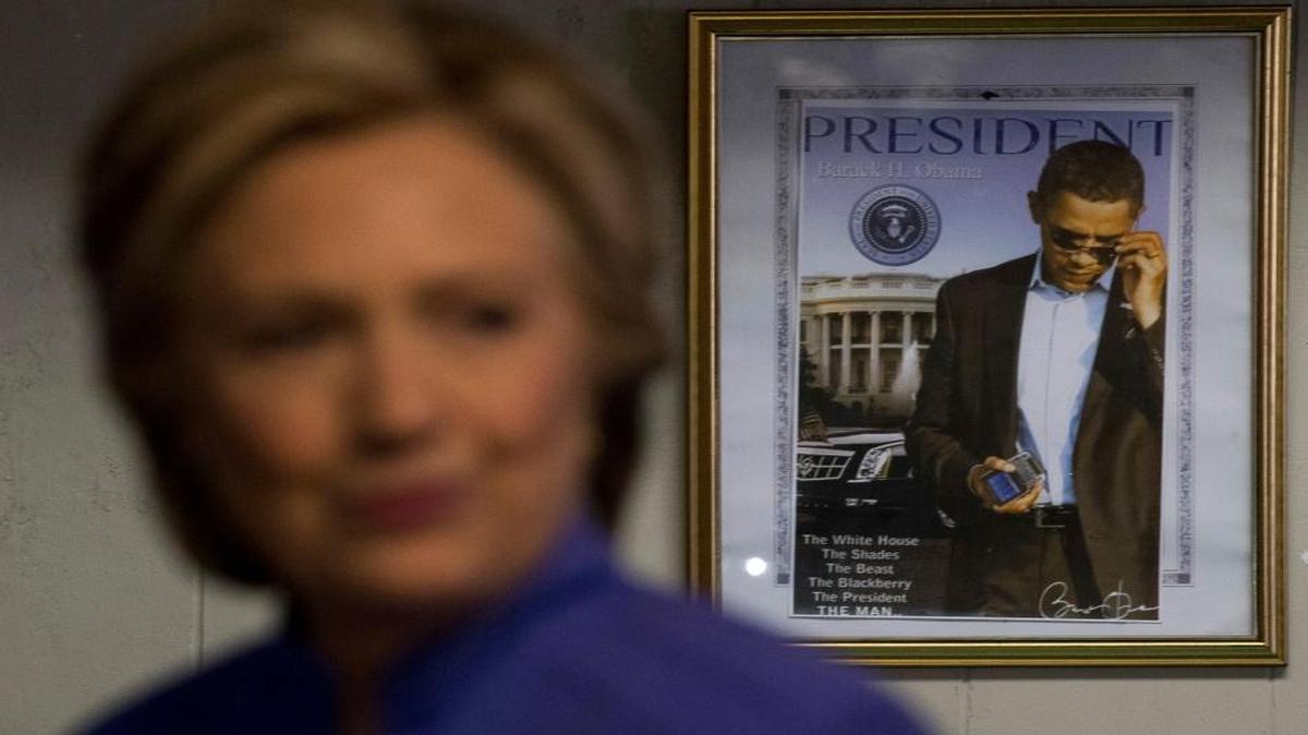 A photograph of President Barack Obama hangs on the wall behind Democratic presidential candidate Hillary Clinton as she greets people at Betty’s Soul Food Restaurant in Fort Lauderdale, on Sunday.