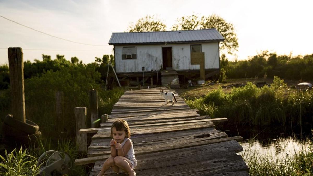 Amiya Brunet, 3, sits on the bridge that leads to her home that frequently floods in Isle de Jean Charles, La., on April 7, 2016. A $48 million grant for Isle de Jean Charles is the first allocation of federal tax dollars to move an entire community struggling with the effects of climate change.