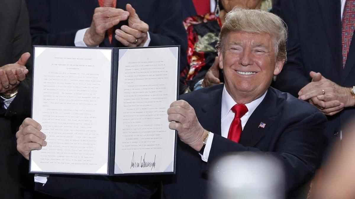 In this Dec. 4, 2017, file photo, President Donald Trump holds up a signed proclamation to shrink the size of Bears Ears and Grand Staircase Escalante national monuments at the Utah State Capitol in Salt Lake City.
