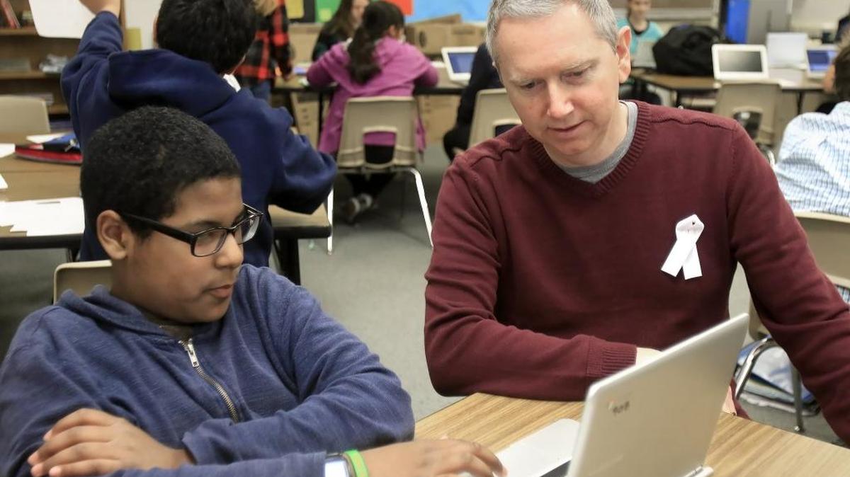 Seventh-grade students in Laguna Middle School teacher Marc Townsend’s world history class had just finished a unit on Islam when the Paris attacks happened. Townsend, with his colleagues, decided to create a new unit on refugee relief. Students are not debating the politics of whether to bring Syrian refugees into the U.S. but are investigating refugee crises around the world. Above, Jacob Edwards, 12, works on the project with teacher, Marc Townsend, during class in December.