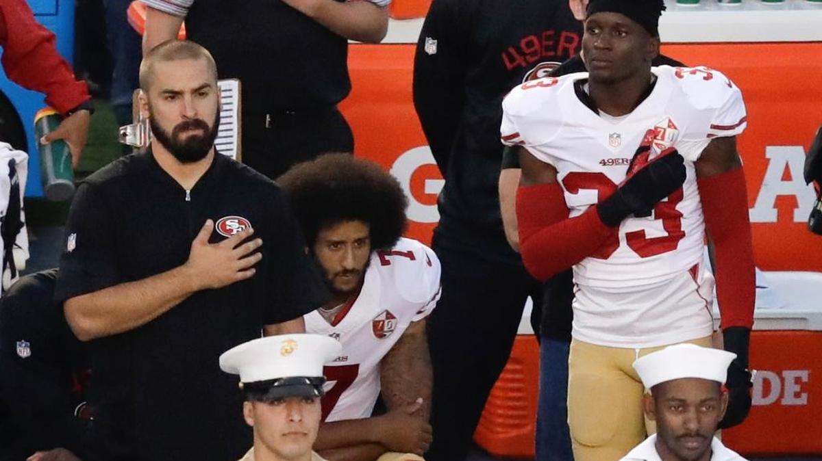 San Francisco 49ers quarterback Colin Kaepernick, middle, sits during the national anthem before an NFL preseason football game against the San Diego Chargers on Thursday, Sept. 1, in San Diego.