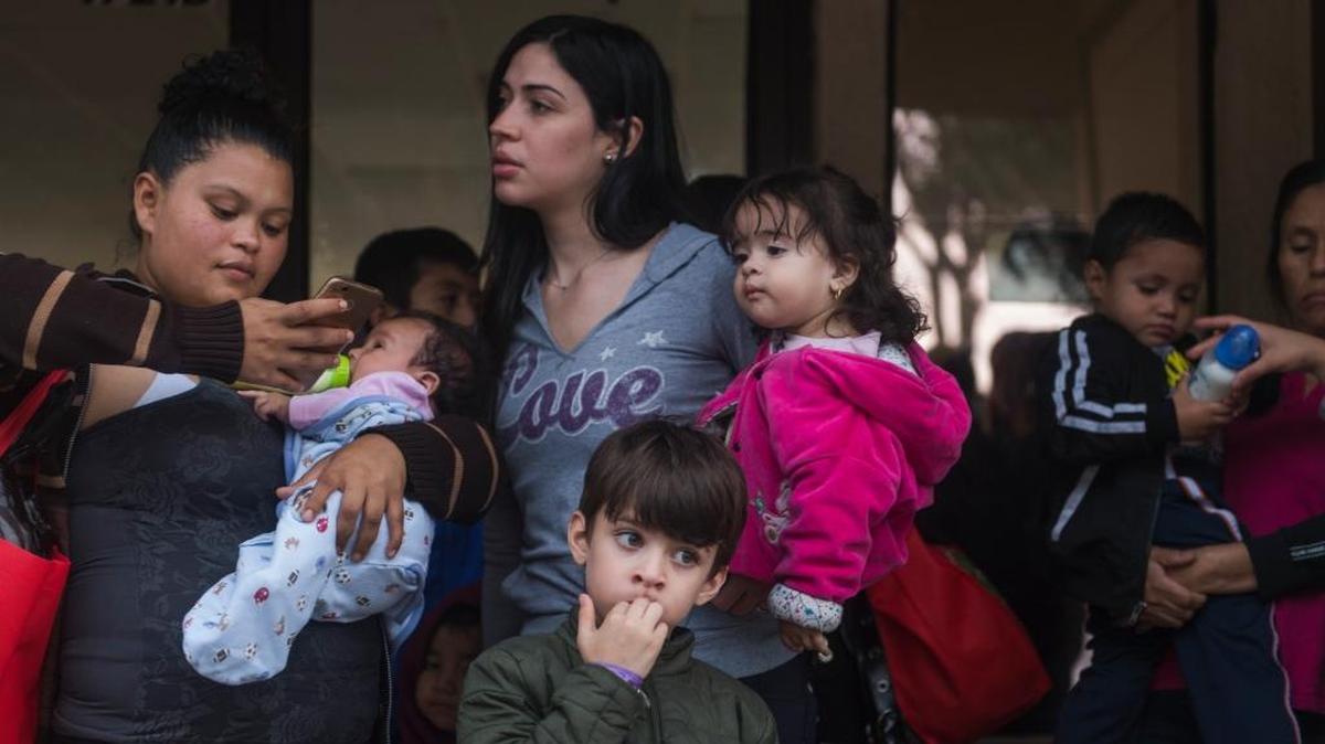 In a Tuesday, June 19, 2018 photo, Central American migrant families wait to be taken to the McAllen bus station from the Catholic Charities Humanitarian Respite Center, in McAllen, Texas. The families were processed and released by U.S. Customs and Border Protection, and then taken to the center, where they were provided with clean clothes, a shower and meal before embarking to their final destinations.