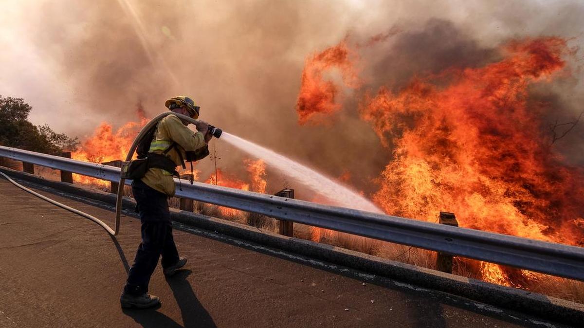 A firefighter battles a fire along the Ronald Reagan (118) Freeway in Simi Valley, Calif., Monday, Nov. 12, 2018.