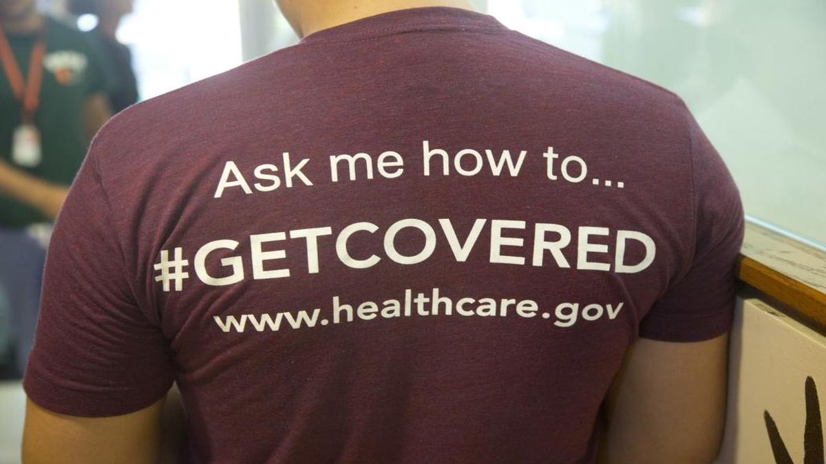 In this March 15, 2014 file photo,a volunteer health care worker wears a T-shirt, getting people to sign up for the new health care programs, in Miami.