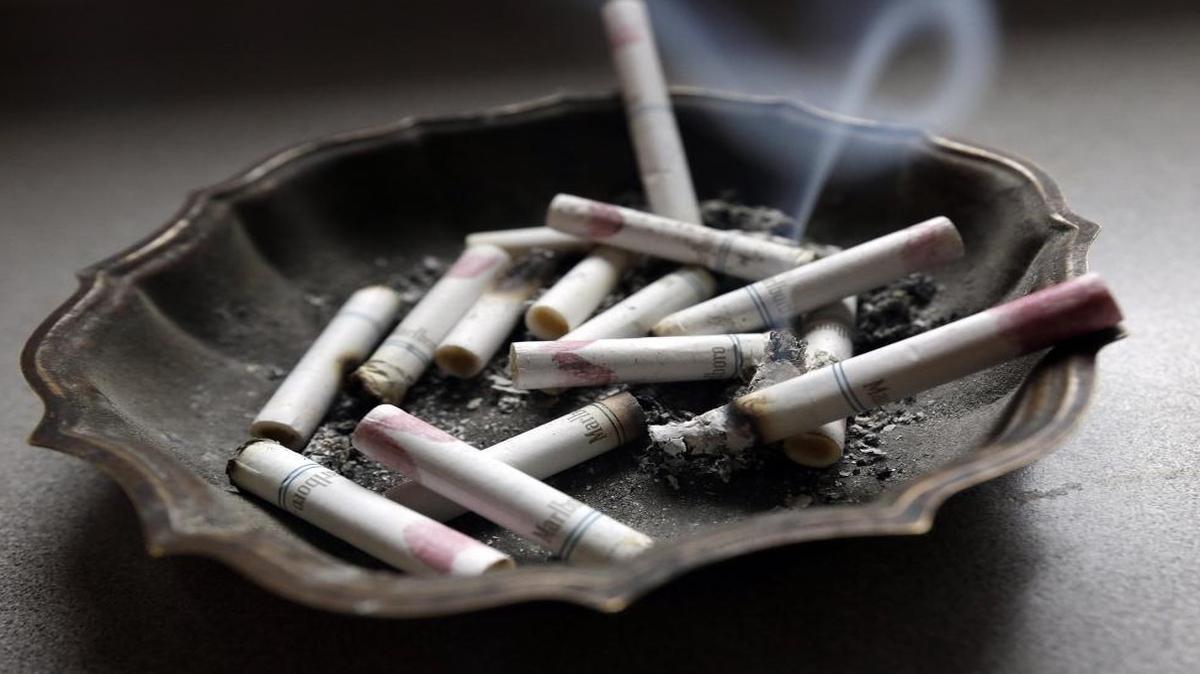 A cigarette burns in an ashtray.