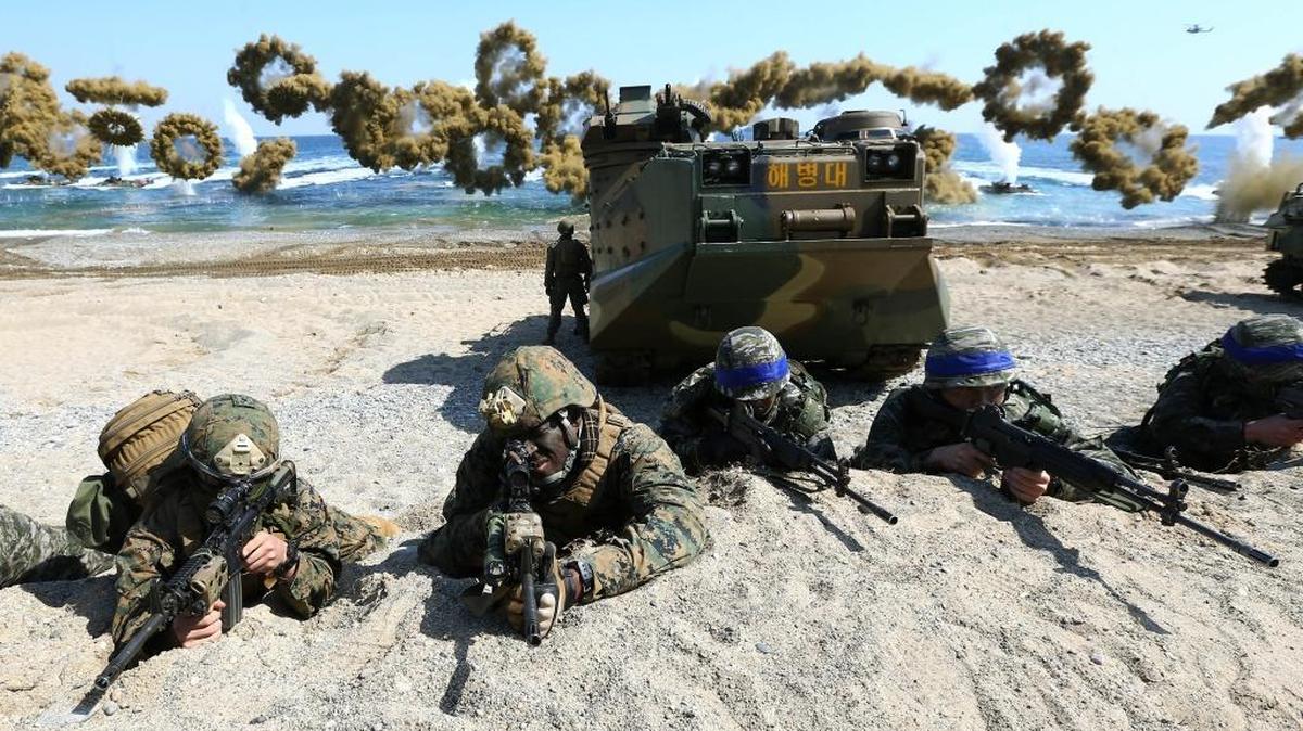 U.S. Marines, left, and South Korean Marines, wearing blue headbands on their helmets, take positions after landing on the beach during the joint military combined amphibious exercise, in Pohang, South Korea, in March.