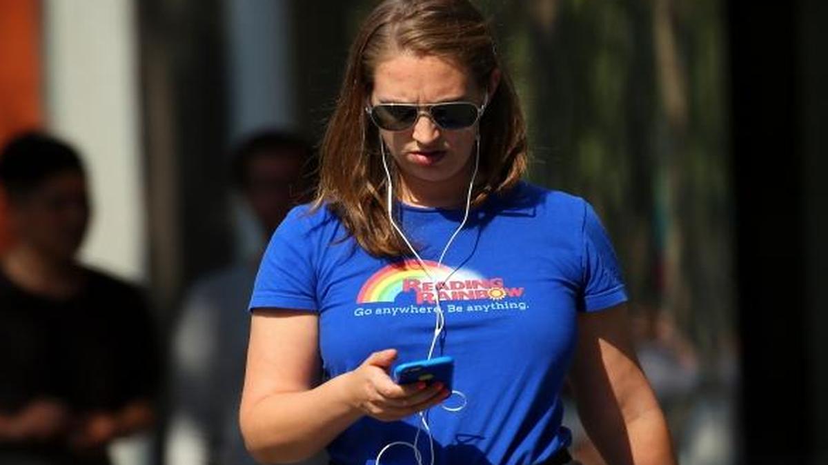 A pedestrian checks her phone in downtown Palo Alto on Aug. 19, 2016.