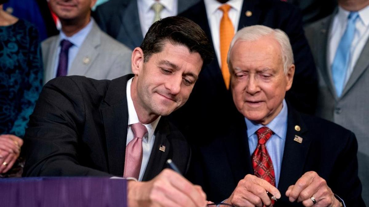 Speaker of the House Paul Ryan, R-Wis., center, accompanied by Senate Finance Committee Chairman Orrin Hatch, R-Utah, right, signs the final version of the GOP tax bill during an enrollment ceremony at the Capitol in Washington, Thursday, Dec. 21, 2017.