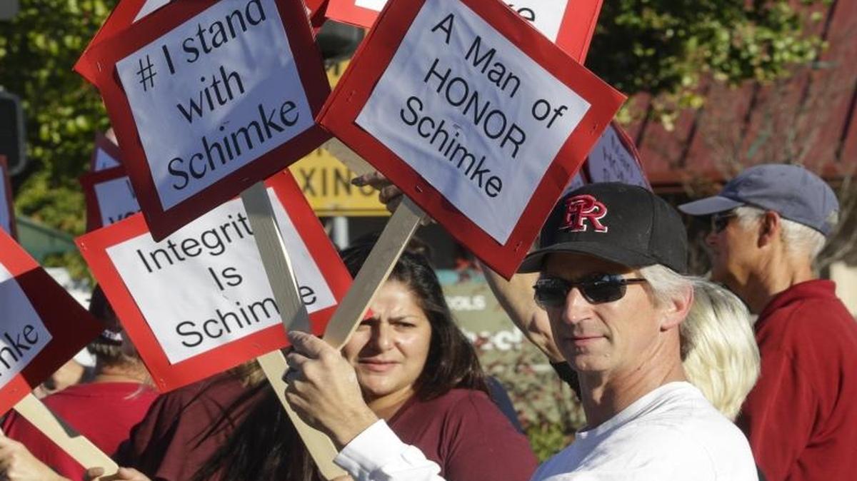 Supporters of Paso Robles football coach Rich Schimke waved placards on Niblick Road near the High School and District offices. Parent of former player and current student Gary Pasky is in foreground.