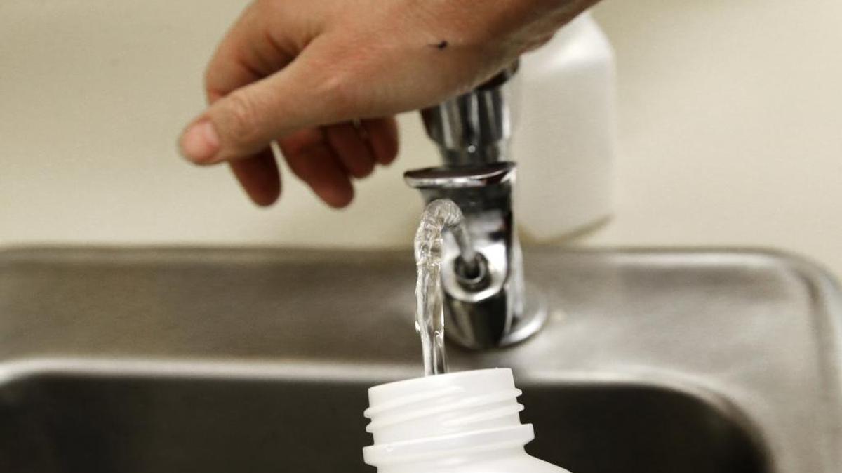 In this photo taken May 3, 2016, Donna McNeal, of Orion Environmental Services, collects a water sample from a classroom drinking fountain in Tacoma, Wash.