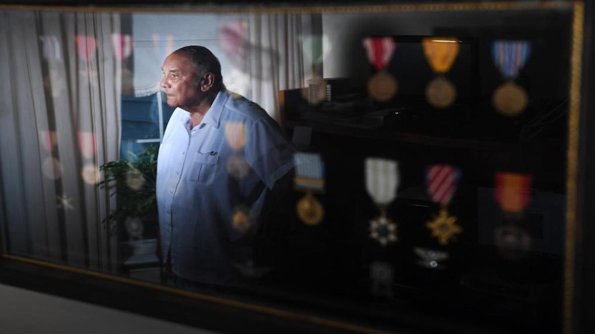 Carl Johnson, 90, seen in a reflection at his home in Ashburn, Va., was a member of the famed Tuskegee Airmen.
