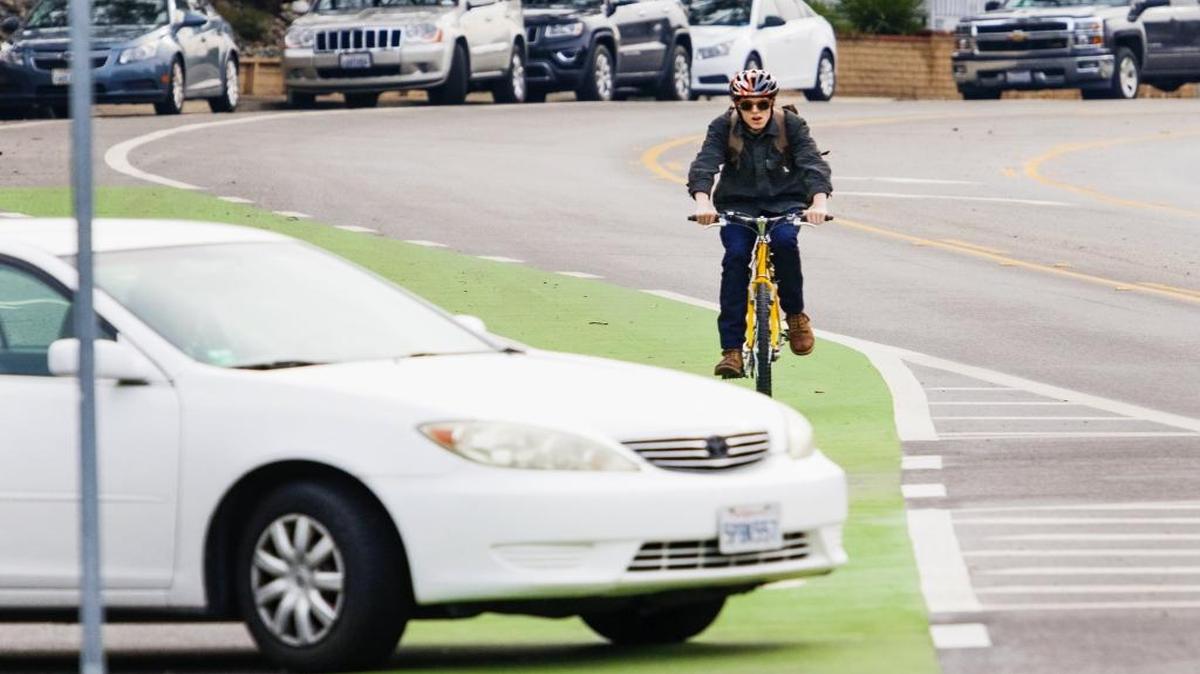 A cyclist bikes towards Cal Poly in the green bike lane along California Boulevard, which was added to increase safety for bicyclists.