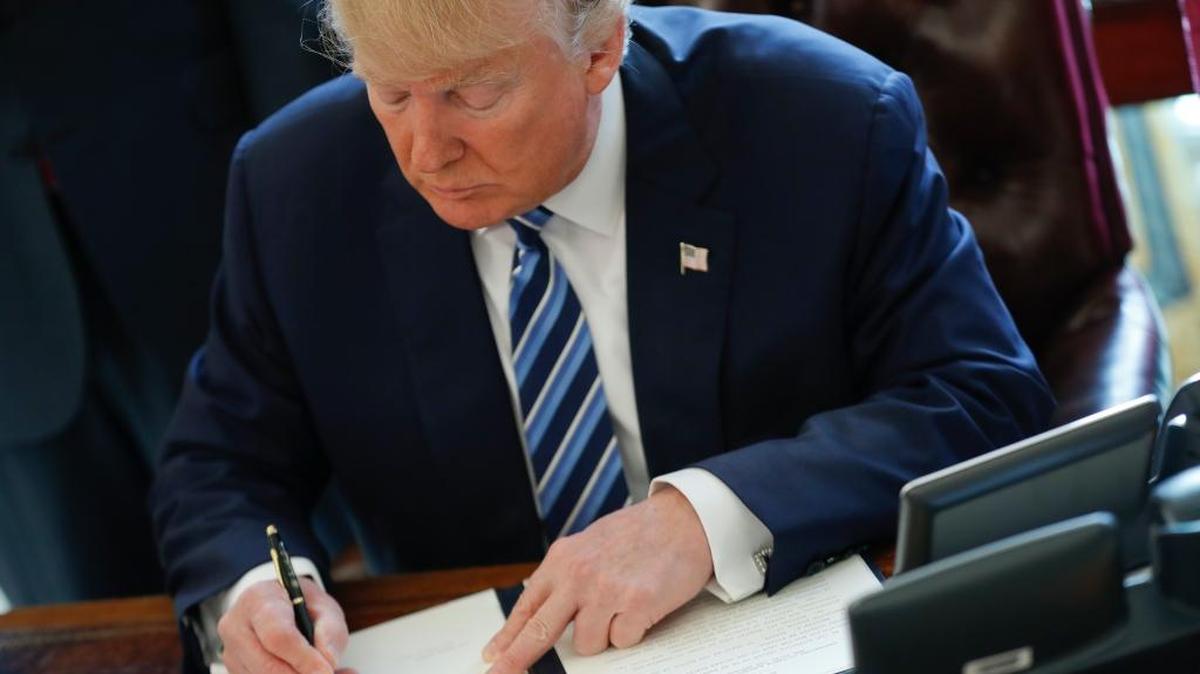 President Donald Trump signs an executive order in the Oval Office of the White House in Washington, Thursday, Feb. 9, 2017. Trump signed three executive orders related to reducing crime.