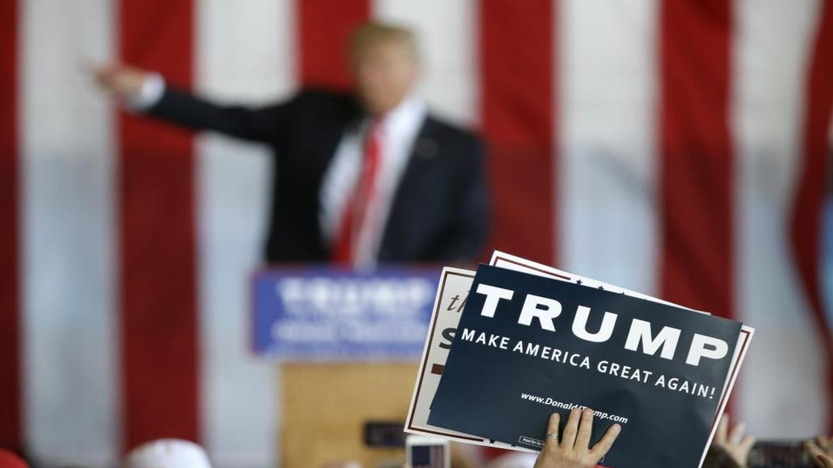 A supporter holds a sign as Republican presidential candidate Donald Trump speaks at a rally.