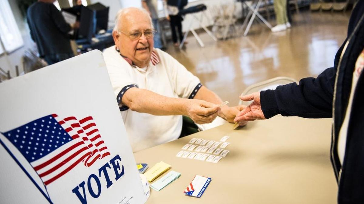 Poll worker Ray Black hands out stickers to voters at Hanover's Ward 3 polling station April 26 at the Utz Pavillion in Hanover, Pa.