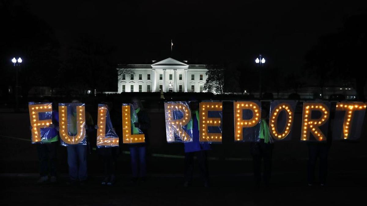 Members of the protest group Herndon Reston Indivisible and Kremlin Annex hold signs outside the White House in Washington on March 25, 2019.