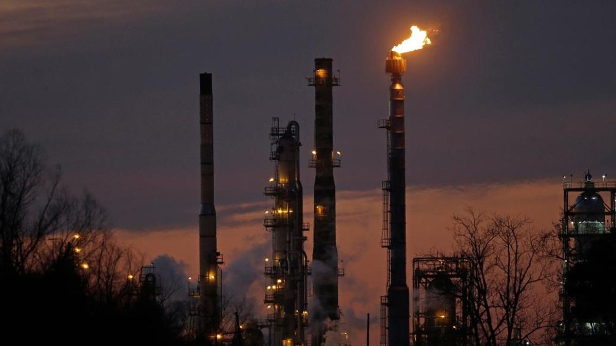 In this Feb. 13, 2015 file photo, stacks and burn-off from the ExxonMobil refinery are seen at dusk in St. Bernard Parish, La.