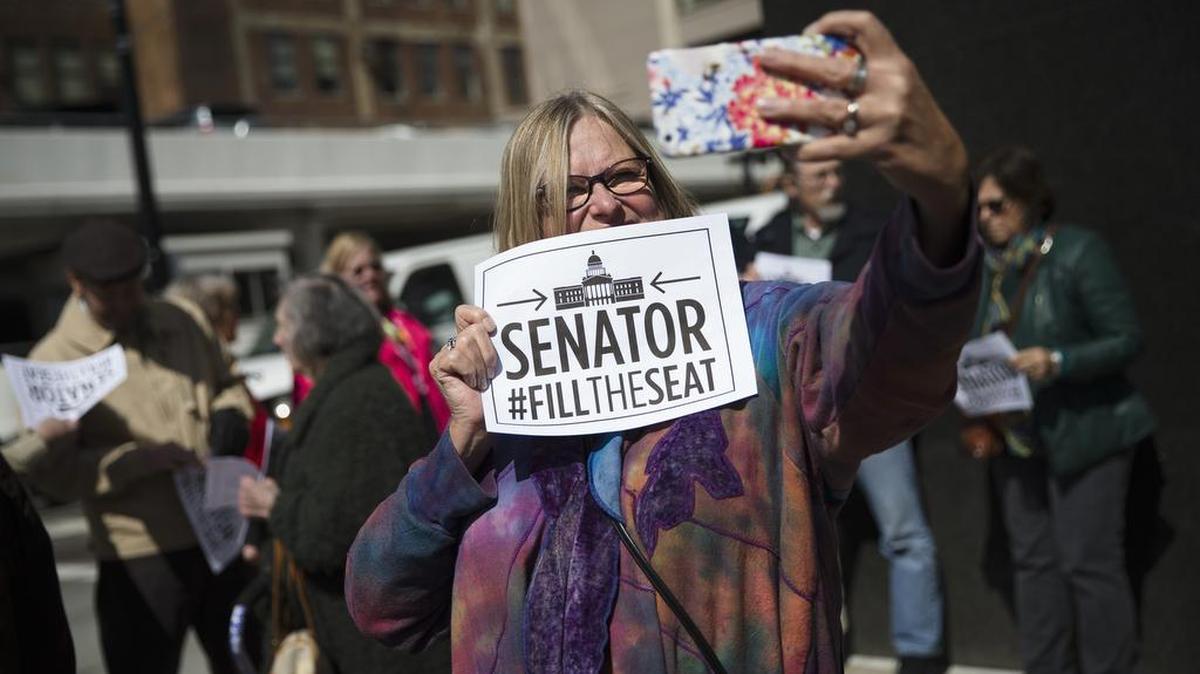Terry Durgin, of Dayton, Ohio, takes a selfie with the hashtag #FILLTHESEAT as she pickets outside the office of Sen. Rob Portman, R-Ohio, on Monday in Cincinnati. A coalition of liberal groups staged rallies around the country on Monday targeting Republican senators who oppose confirmation hearings for President Barack Obama’s Supreme Court nominee Merrick Garland.