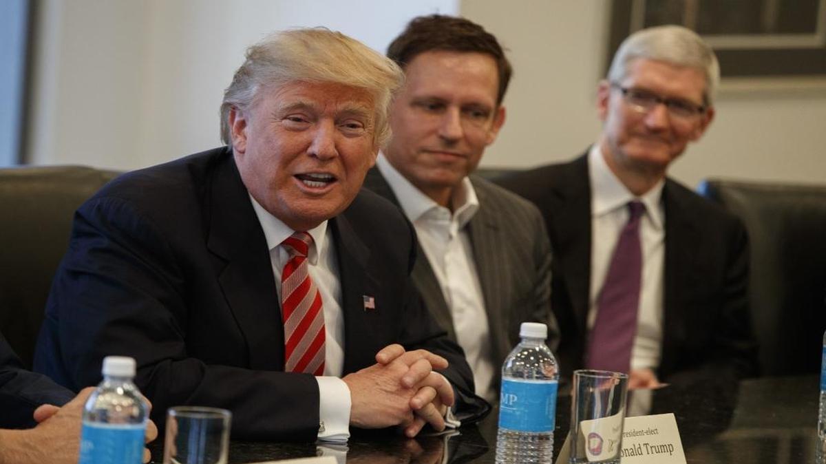 Apple CEO Tim Cook, right, and PayPal founder Peter Thiel, center, listen as President-elect Donald Trump speaks during a meeting with technology industry leaders at Trump Tower in New York, Wednesday, Dec. 14, 2016.