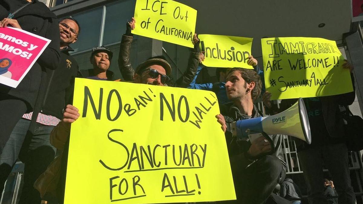 Protesters hold up signs outside a courthouse where a federal judge heard arguments in the first lawsuit challenging President Donald Trump's executive order to withhold funding from communities that limit cooperation with immigration authorities on April 14, 2017, in San Francisco.