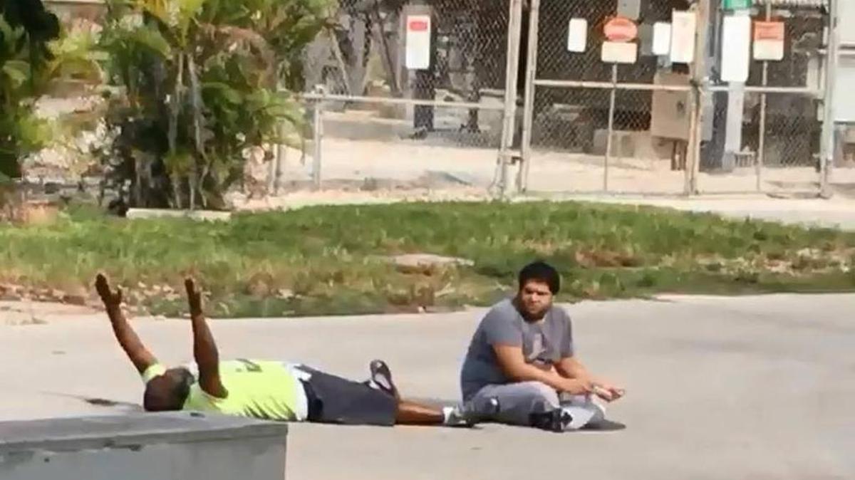 Cellphone video shows caretaker Charles Kinsey lying in the street with his hands up. Kinsey was shot by North Miami, Fla., police responding to a 911 call on Monday, July 18, 2016. Kinsey was trying to convince an autistic man, seen at right, to return to a mental health facility when the police arrived. When the autistic man failed to comply with officers’ orders, one of them opened fire, hitting Kinsey in the leg. Screengrab of video provided by Hilton Napoleon