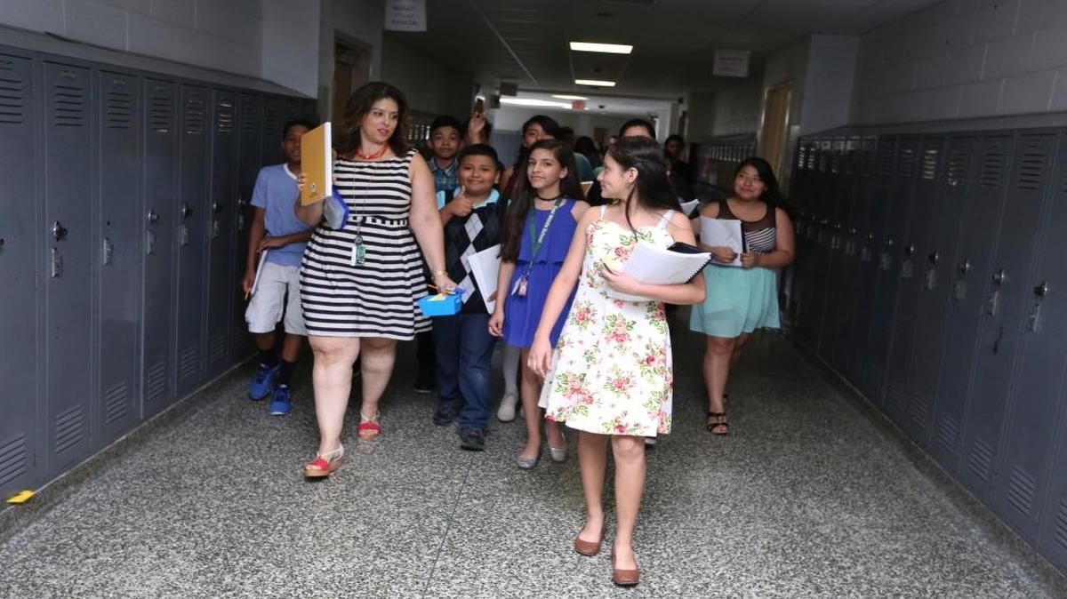 In this Wednesday, June 14, 2017, photo, Maria Victoria Mendoza's six grade class walks back to their classroom in Brentwood, N.Y.