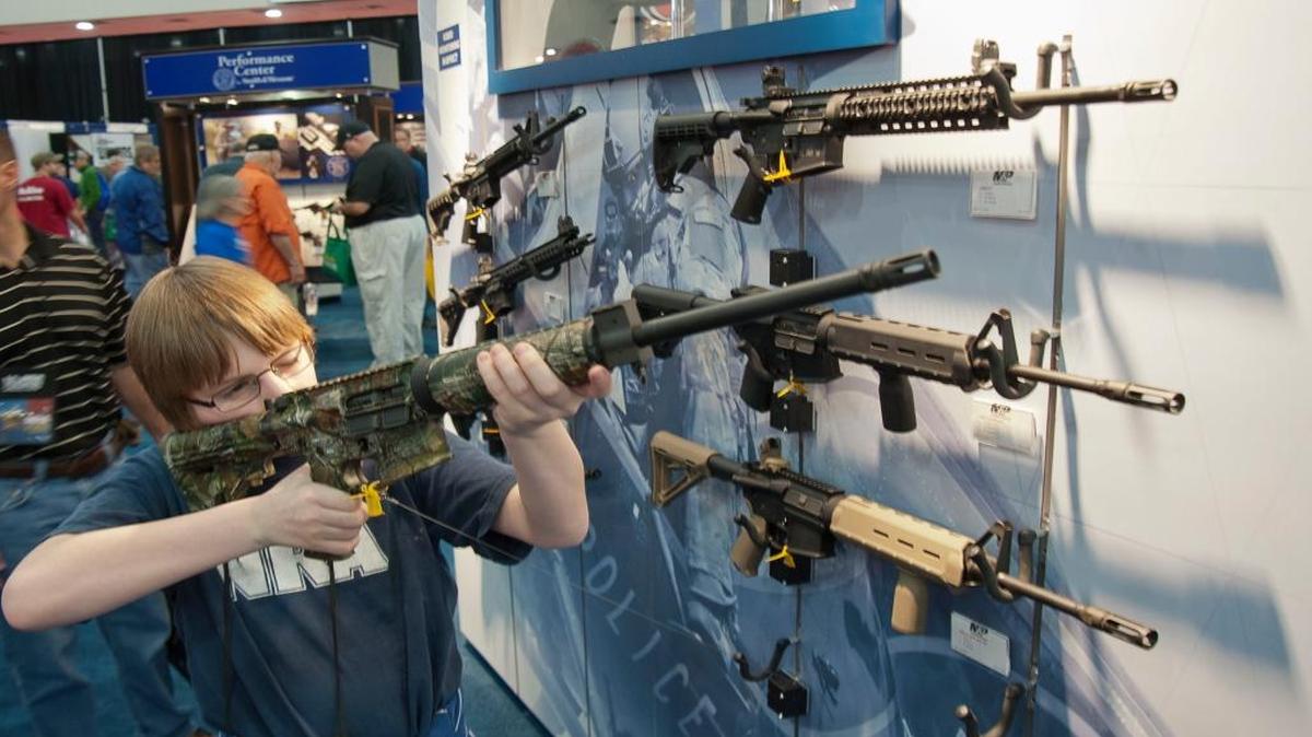 A young man who chose not to give his name sizes-up an assault-style rifle during the National Rifle Association’s annual convention May 3, 2013, in Houston.