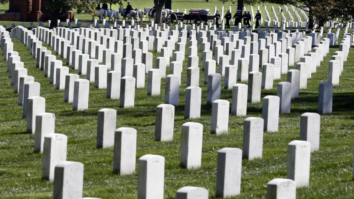 In this Oct. 22, 2012 file photo, a funeral procession passes behind rows of graves at Arlington National Cemetery in Arlington, Va.