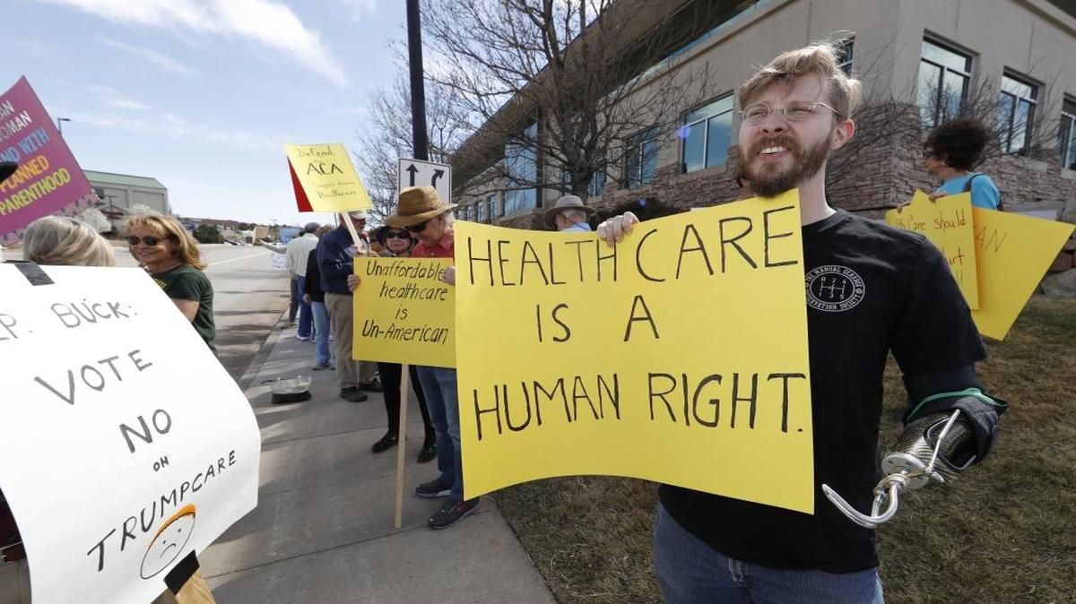 In this Wednesday, March 22, 2017 photo, Spencer Worley of Castle Rock, Colo., joins other protesters against the failed Republican-proposed health care act in a demonstration outside the office of U.S. Rep. Ken Buck in Castle Rock, Colo.