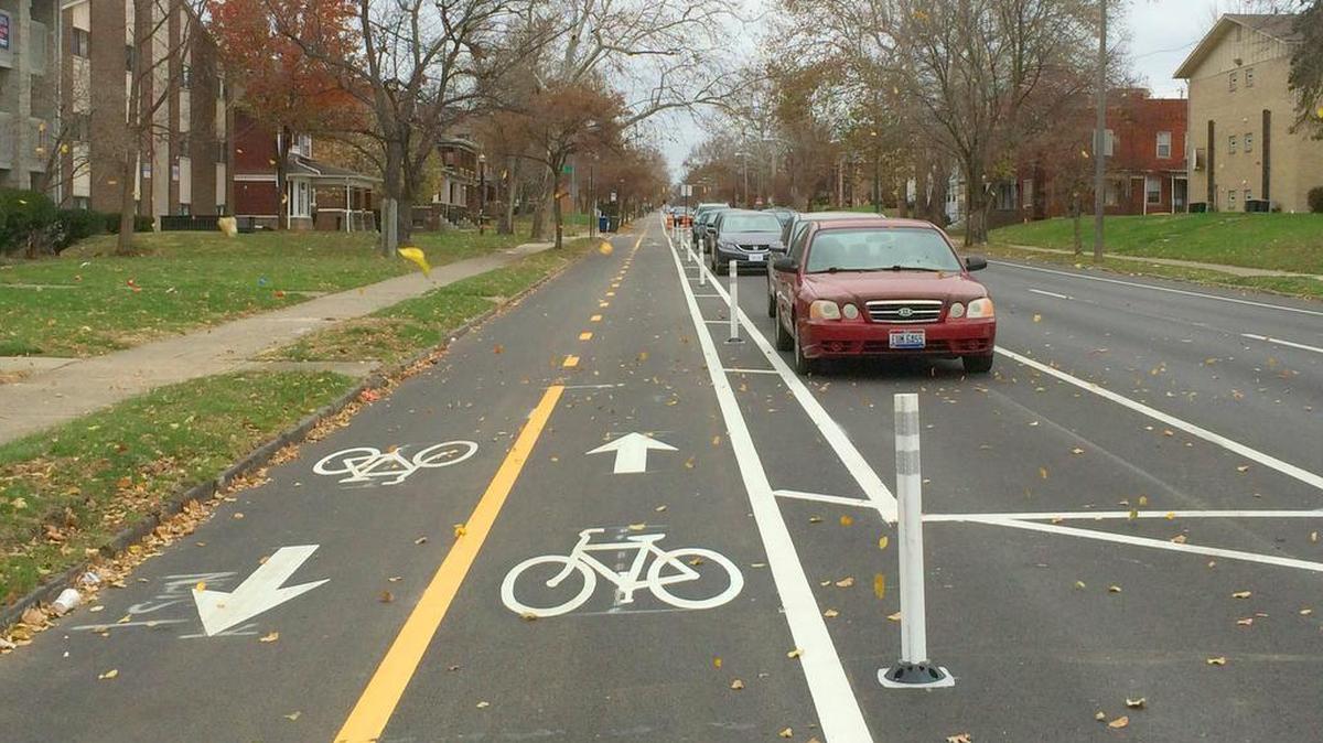 A protected bike lane, also known as a bicycle track, in the city of Columbus, Ohio. Note that bollards and parked cars separate cyclists from traffic lanes.