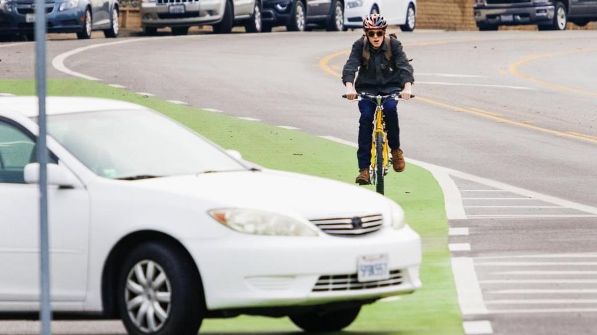 A cyclist bikes toward Cal Poly in the green bike lane along California Boulevard, which was added to increase safety for bicyclists.
