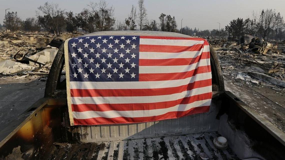 A flag is draped on the back of a truck destroyed by fire in Santa Rosa.