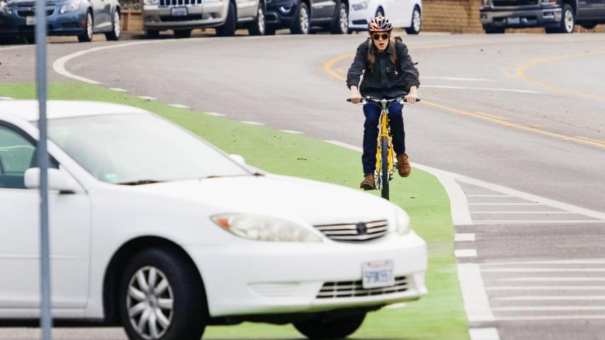 A cyclist bikes towards Cal Poly in the green bike lane along California Blvd., which was added to increase safety for bicyclists.