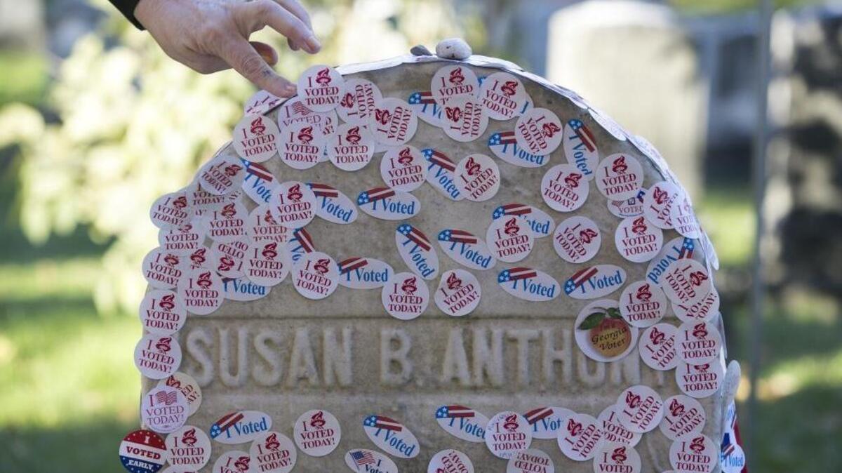 A woman places a voting sticker on the headstone of Susan B. Anthony, a women’s suffrage pioneer, on Election Day in Rochester, New York, on Nov. 8, 2016.