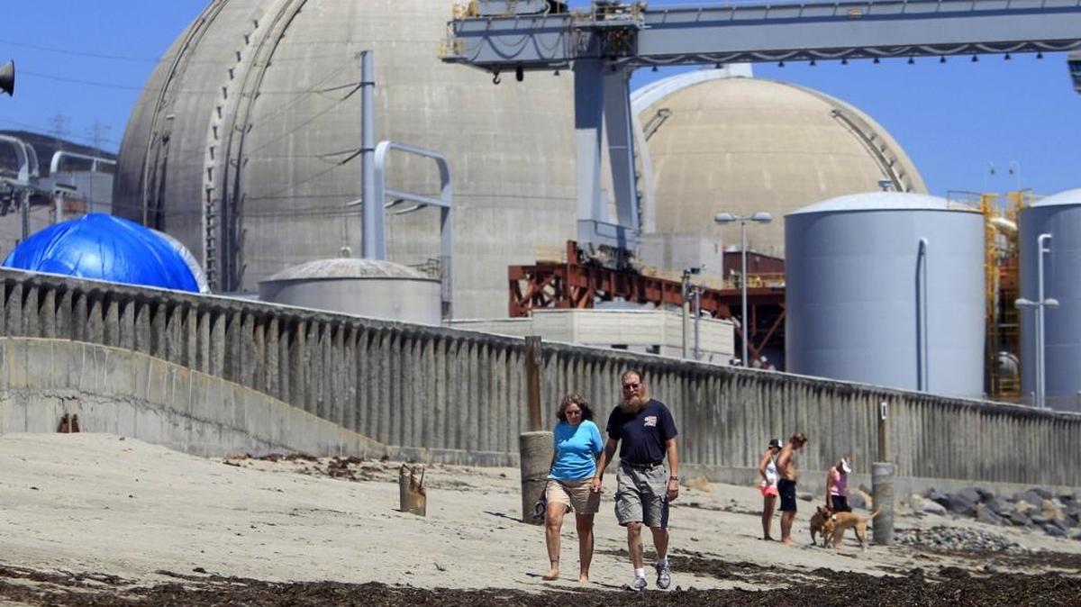Beachgoers roam the San Clemente sand near the San Onofre nuclear power plant in 2011. The allocation of costs for the plant’s shutdown is drawing scrutiny.