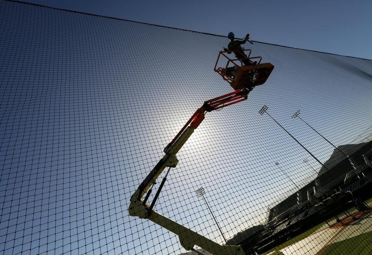 A worker puts the final touches on the new netting at Cal Poly's renovated Baggett Stadium. The new netting is meant to protect fans from foul balls and improve the viewing experience.
